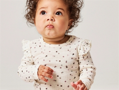 Baby klædt i Name It ribbody i råhvid nuance med flæser ved skuldrene