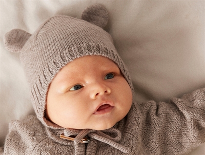 Baby klædt i Name It merinould hue i beige nuance med bamseører