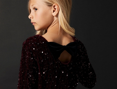 Pige iført Name It burgundy pailletkjole med sort sløjfe