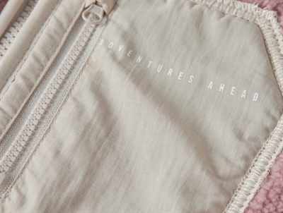 Detalje af brystlomme med tekst Adventures Ahead på Name It teddy jakke