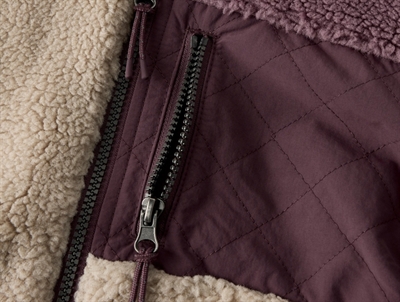 Detalje af lynlåslomme på Name It Kids teddy jakke i råhvid og lilla nuance