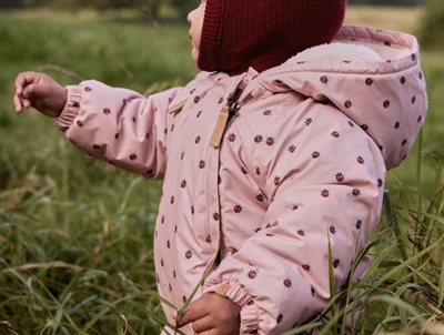 Baby i Lil\' Atelier flyverdragt rosa med mariehøneprint udendørs