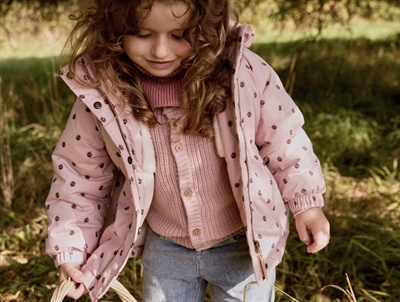 Barn iført Lil\' Atelier jakke rosa med mariehøneprint udendørs