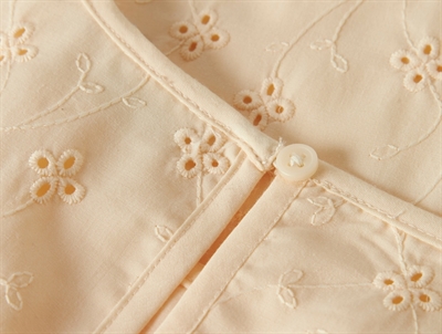 detalje af knaplukning bagpå broderet top fra Name It i buttercream