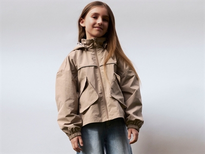 Pige iklædt Name It jakke i beige nuance med aftagelig hætte  