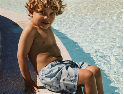Dreng iklædt Name It badeshorts blå nuance med dinosaur print til børn