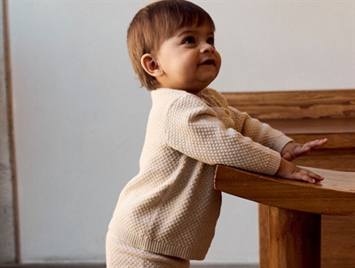 Barn iklædt i Name It strik cardigan i beige nuance med struktur