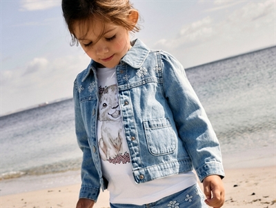 Pige iklædt Name It denimjakke i lys blå nuance med blomsterbroderi 