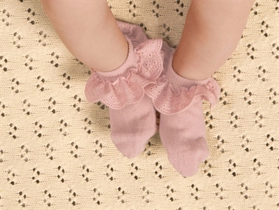 Baby iklædt Lil' Atelier strømper i rosa nuance med flæsekant