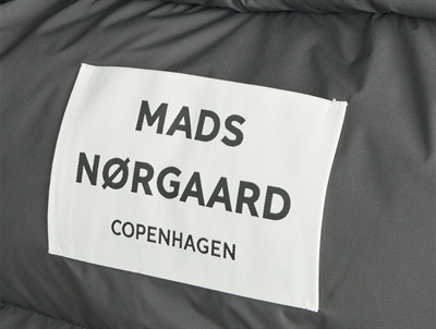 Nærbillede af Mads Nørgaard logo på mørkegrå puffetaske