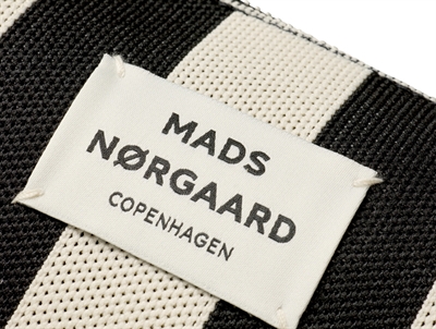 Nærbillede af Mads Nørgaard logo på sort og hvid stribet taske
