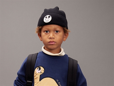 Barn iført sort beanie med badge fra Mini Rodini