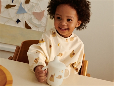 Liewood Merle cape hagesmæk i ecru med elefant print set forfra