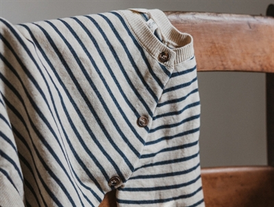 Petit Piao strikcardigan med knapper i siden på en stol